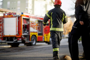 Fireman in uniform in front of fire truck going to rescue and pr
