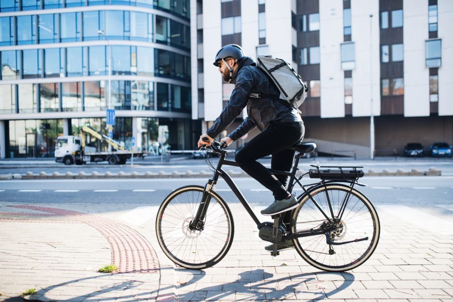 Male courier with bicycle delivering packages in city. Copy space.